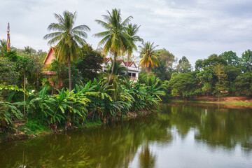 Fototapeta na wymiar Scenery view of the lake with a house behind the palm trees in Cambidia
