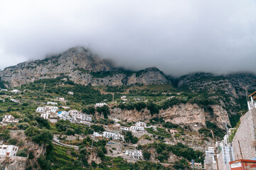 Fototapeta na wymiar view of the village high in the mountains. Thick gray clouds cover the top. Highland Housing Concept. Olive plantations, houses and hotels. Italian coast Castello Lauritano in Agerola San Lazzaro