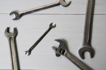 Several vintage wrenches on a light wooden background view from the top