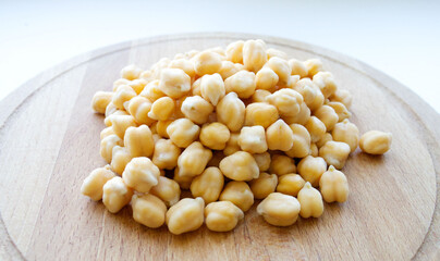 bean, closeup of chickpea chickpea, on a wooden surface, on a light background. Illuminated by light. The benefits or harms of chickpeas. High carbohydrate, protein and fatty acid product