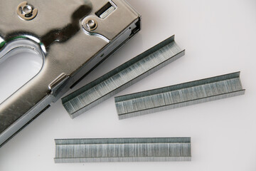 Concept of repair and construction. Construction stapler with brackets on a gray background top view