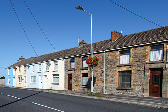 Penclawdd, UK: August 18, 2018: Traditional terraced fishermen's cottages in a coastal village in Wales. Front view, diminishing perspective with a blue sky background. Illustrative Editorial