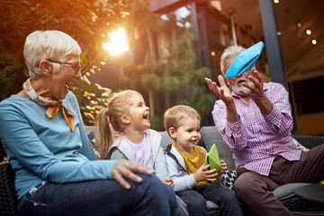 Grandpa entertains children with paper sailboat