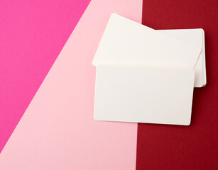 stack of rectangular white paper blank business cards on a pink background