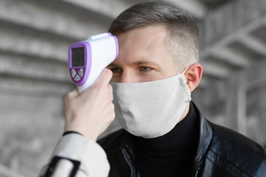 Operator check fever by digital thermometer visitor at information counter for scan and protect from coronavirus COVID-19.