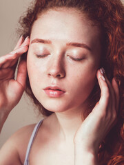 Naklejka premium a beautiful girl with freckles and curly hair washed her face and closed her eyes. Skin hydration concept. No makeup, close-up face