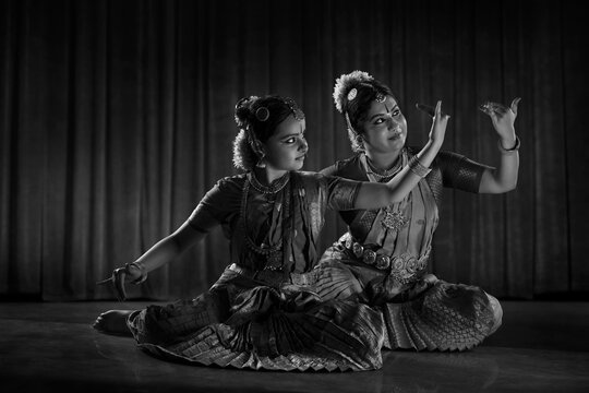 Black and white image of a bharatnatyam dancer teaching her young student.  
