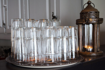 Empty glassfuls on a metal tray next to an oriental-style decorative candlestick. Restaurant...