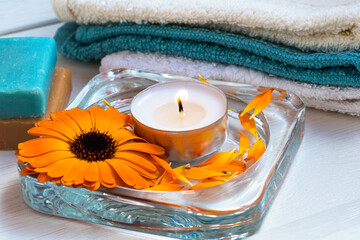 Obraz na płótnie Canvas Beautiful spa composition.Candle, soft cotton towels, soap and calendula officinalis flower. The concept of health and Alternative medicine.Close-up.