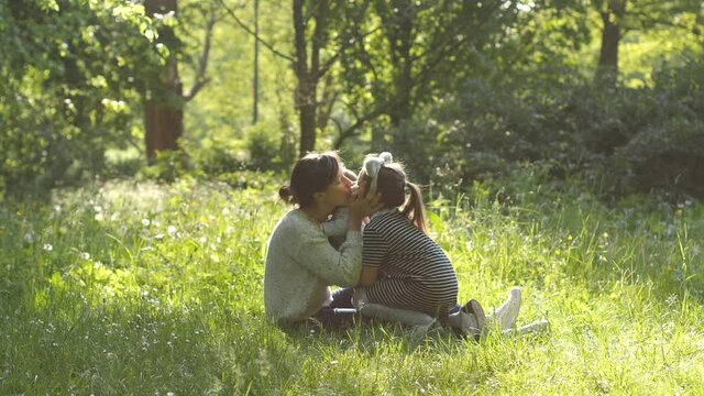 Mother funny play with her daughters elder sister and baby toddler happy family in green park nature