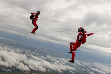 Naklejka na ściany i meble Two sports parachutist build a figure in free fall. Extreme sport concept.