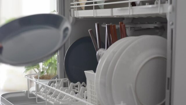 食洗機に皿を入れる女性