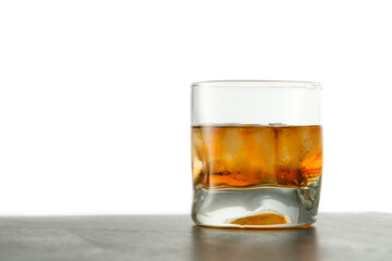 Glass of aged golden whiskey with ice cubes on the table. Amber colored alcohol beverage with rocks at the bar