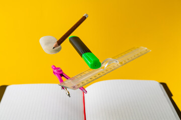 Levitating school supplies for math - notebook, pen, ruler, pencil, divider and eraser on yellow background. Concept of education and creativity