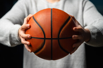 Close up of professional basketball player holding a ball in the hand. Street basketball athlete...