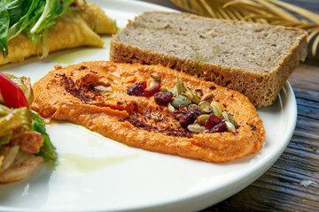 Healthy breakfast - omelet with kimchi and baked peppers hummus in a plate on a wooden background