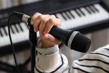Closeup of teenager recording music in home studio. Girl with headphones and microphone recording song