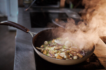 Close up view of cooking process, fish is fryed with mushrooms, onion and vegetables. Thick steam coming from the pan. Appetizing and delicious lunch or dinner. 