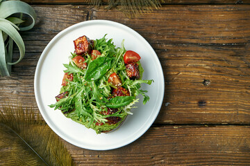 Trend street food - avocado toast with guacamole, arugula and tofu cheese in a white plate on a wooden background. Vegetarian food