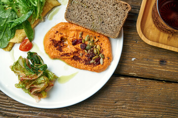 Healthy breakfast - omelet with kimchi and baked peppers hummus in a plate on a wooden background