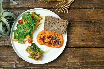 Healthy breakfast - omelet with kimchi and baked peppers hummus in a plate on a wooden background