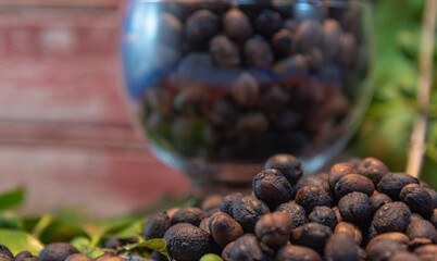 Green and roasted coffee beans (Coffea sp) in glass bowl on wooden rustic background