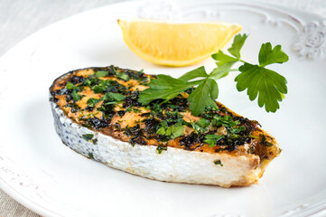 Salmon with parsley and lemon on a white plate. Serving red fish