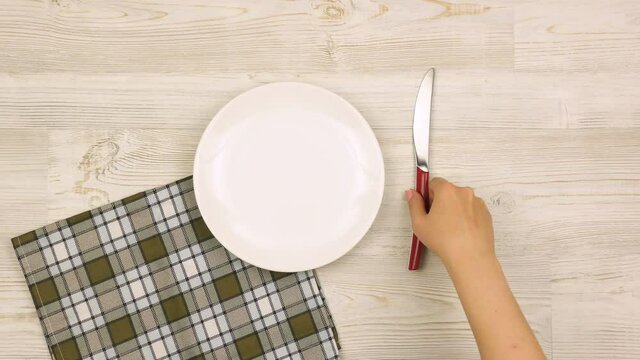 Father's Day table setting with cutlery, hat and mustache on light wooden table. Female hands set the table for the holiday. Top view. 