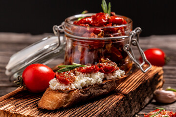 italian sandwiches with cheese and sun dried tomatoes on wooden kitchen board top view. Food recipe background. Close up