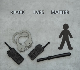 Black Lives Matter flat lay with black paper silhouette, handcuffs, radio stations, baton on grey...