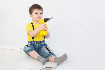 a small boy in a Builder's suit makes repairs on a white background