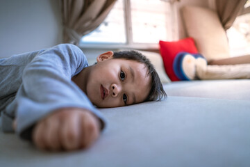 little Asian boy lying on the bed and looking at camera