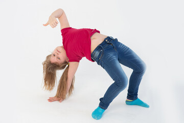 a cheerful beautiful girl in blue jeans and a bright red t shirt does acrobatic tricks on a white background