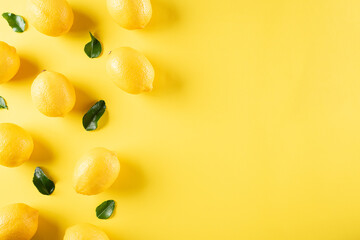 Summer composition made from oranges, lemon and green leaves on pastel yellow background. Fruit minimal concept. Flat lay, top view, copy space.