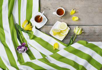 Flat lay with two cups of tea and lemon on striped tablecloth. Top view. 