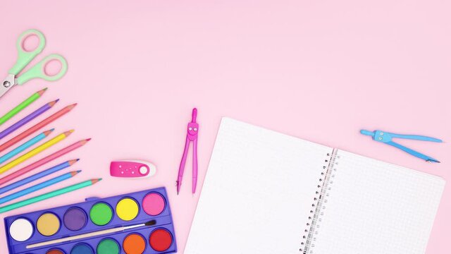 Back to school supplies and open notebook move on bottom of pastel pink background - Stop motion 