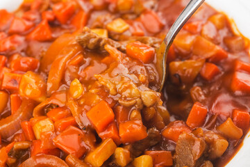 Veal stewed with vegetables in tomato sauce on a board background.