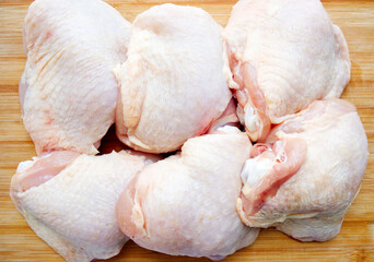 Chicken thighs with skin on a wooden surface. Ingredient, fresh, butchered meat for cooking. Parts...