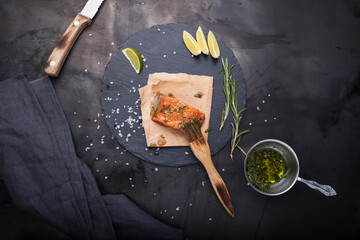A piece of raw salmon with spices and olive oil on a slate plate on a dark metallic background, top view. Preparation of fish. Salmon steak.