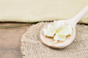 Unrefined, natural shea butter on wooden spoon, natural body lotion