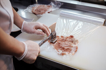 The process of making pork chop, cutlet indoors in the restaurant kitchen. Chef hands are in gloves. 