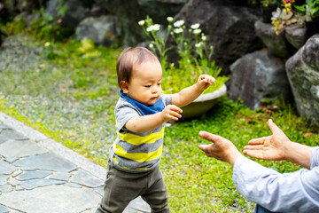 歩き始めた子供がお母さんの手を頼りに歩く