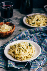 Two Portions of Homemade Pasta Alfredo on White Plate with Grated Cheese Bowl