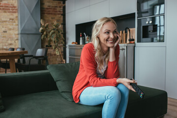 Obraz premium cheerful woman laughing while watching tv at home
