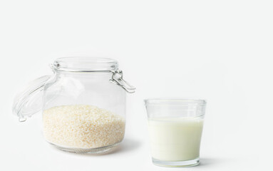 Glass of non-diary animal-free plant based milk dry rice in crystal jar on white kitchen table. Healthy lifestyle vegan diet concept