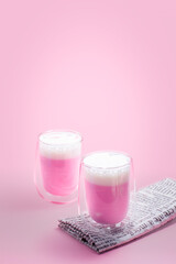 Summer drink concept. Strawberry pink milk with froth milk in clear glass on pink background.