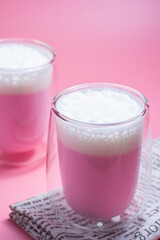 Summer drink concept. Strawberry pink milk with froth milk in clear glass on pink background.