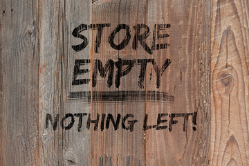 Text "Store empty nothing left" painted black on wooden boards. Boutique shops and stores boarded up. Concept background with text. Protests, riots and looting.