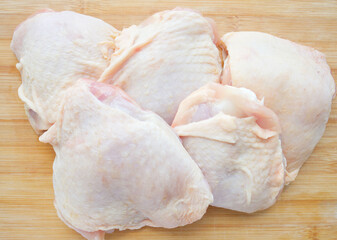 Chopped chicken thighs with skin on a wooden surface. Ingredient, fresh, meat for cooking. Parts of...