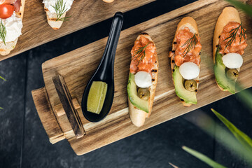 Italian cuisine, antipasti and tapas. Bruschetta of baguette and cottage cheese, tomato, salmon capers, pesto. Serving dishes in a restaurant in white plate.